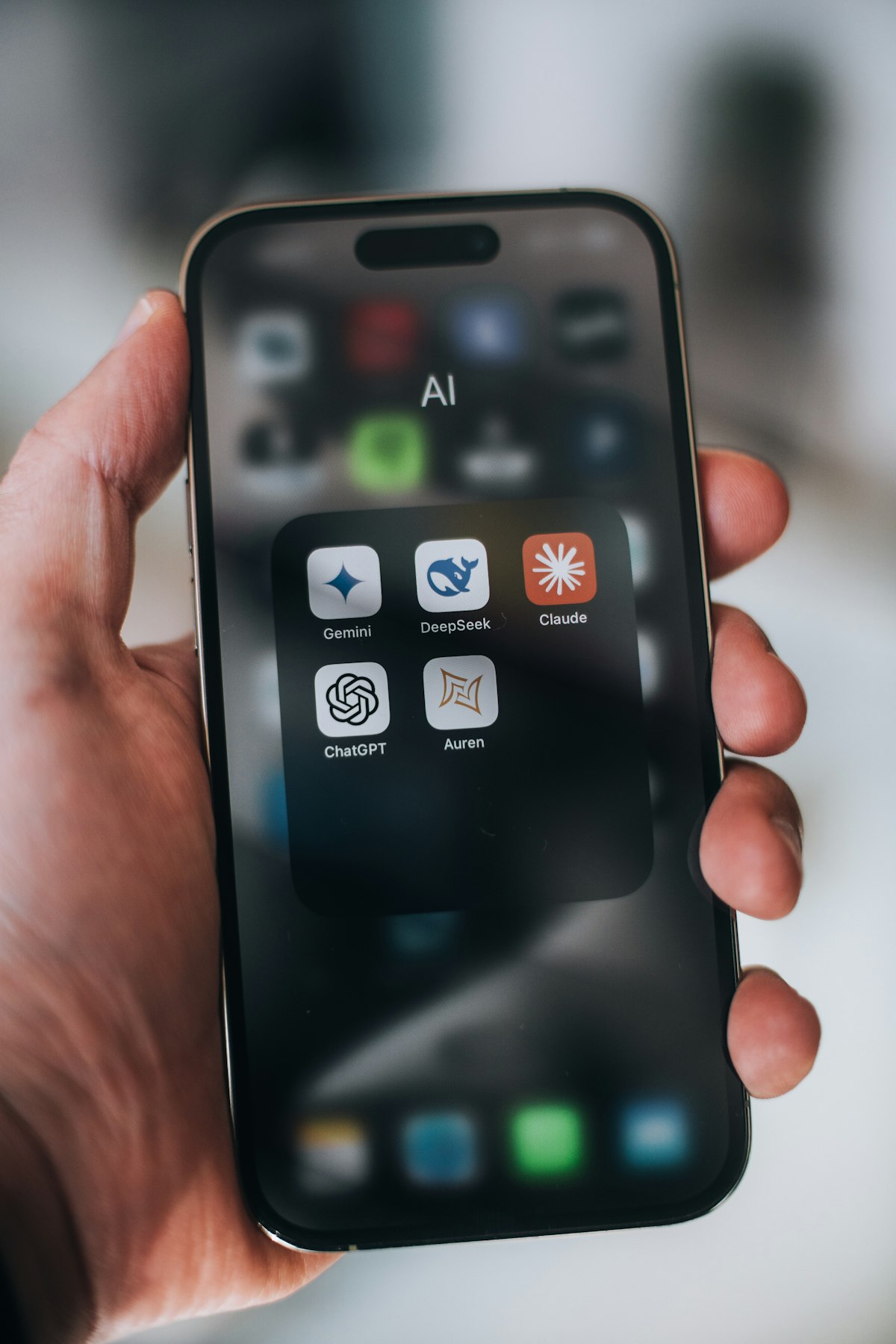 Hand holding a phone with AI app icons