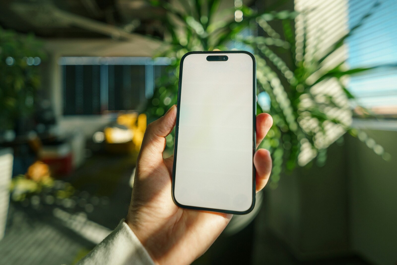 A hand holding a smartphone with a blank screen