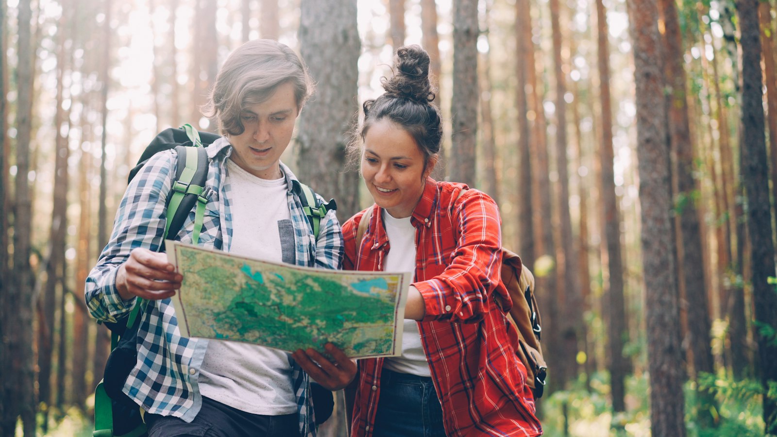 Two hikers reading a map together in a forest