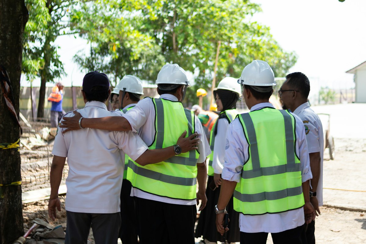 A team in hard hats and safety vests huddled together outdoors